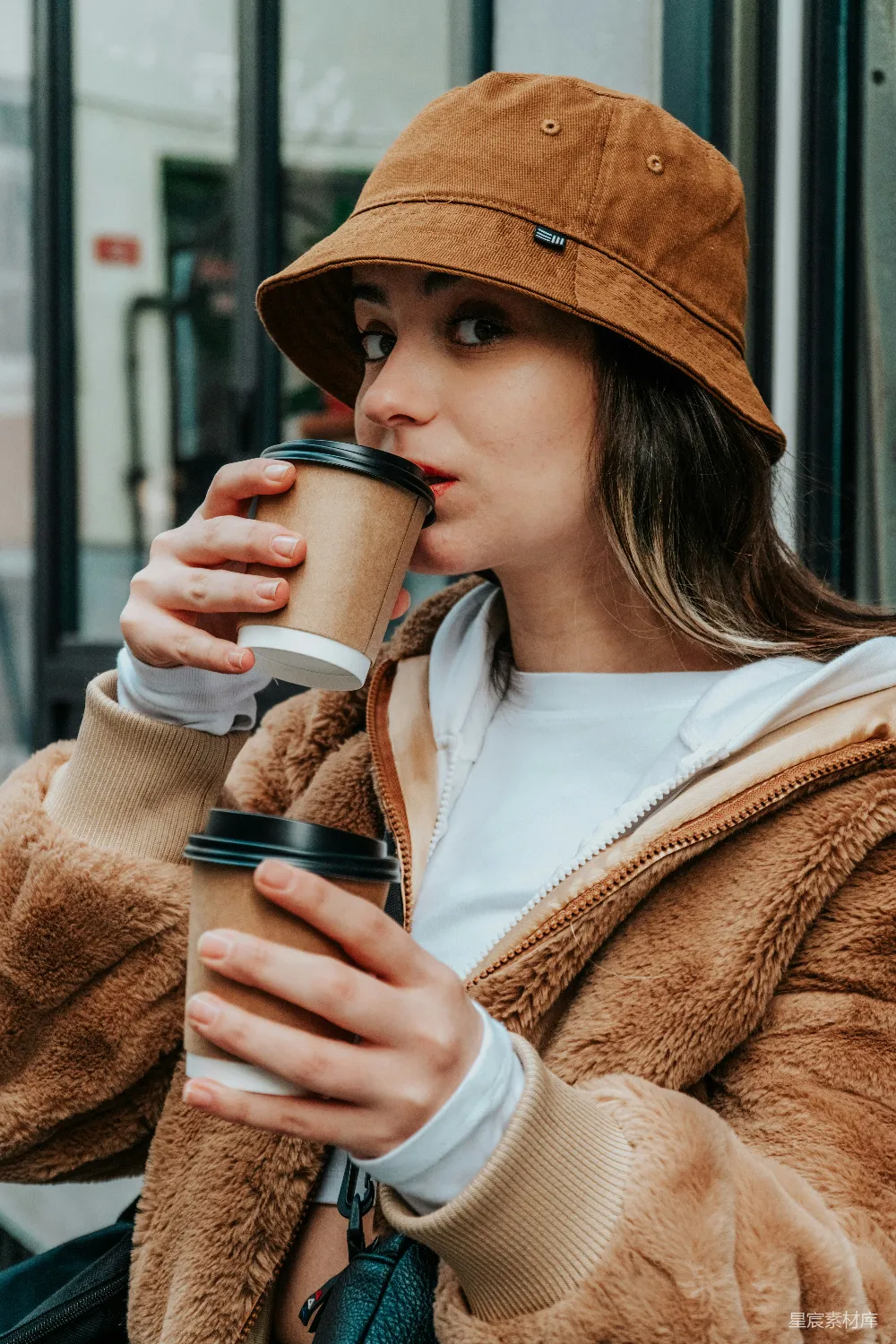 高清摄影 身穿棕色外套的女人手里拿着一个白色的陶瓷 mug