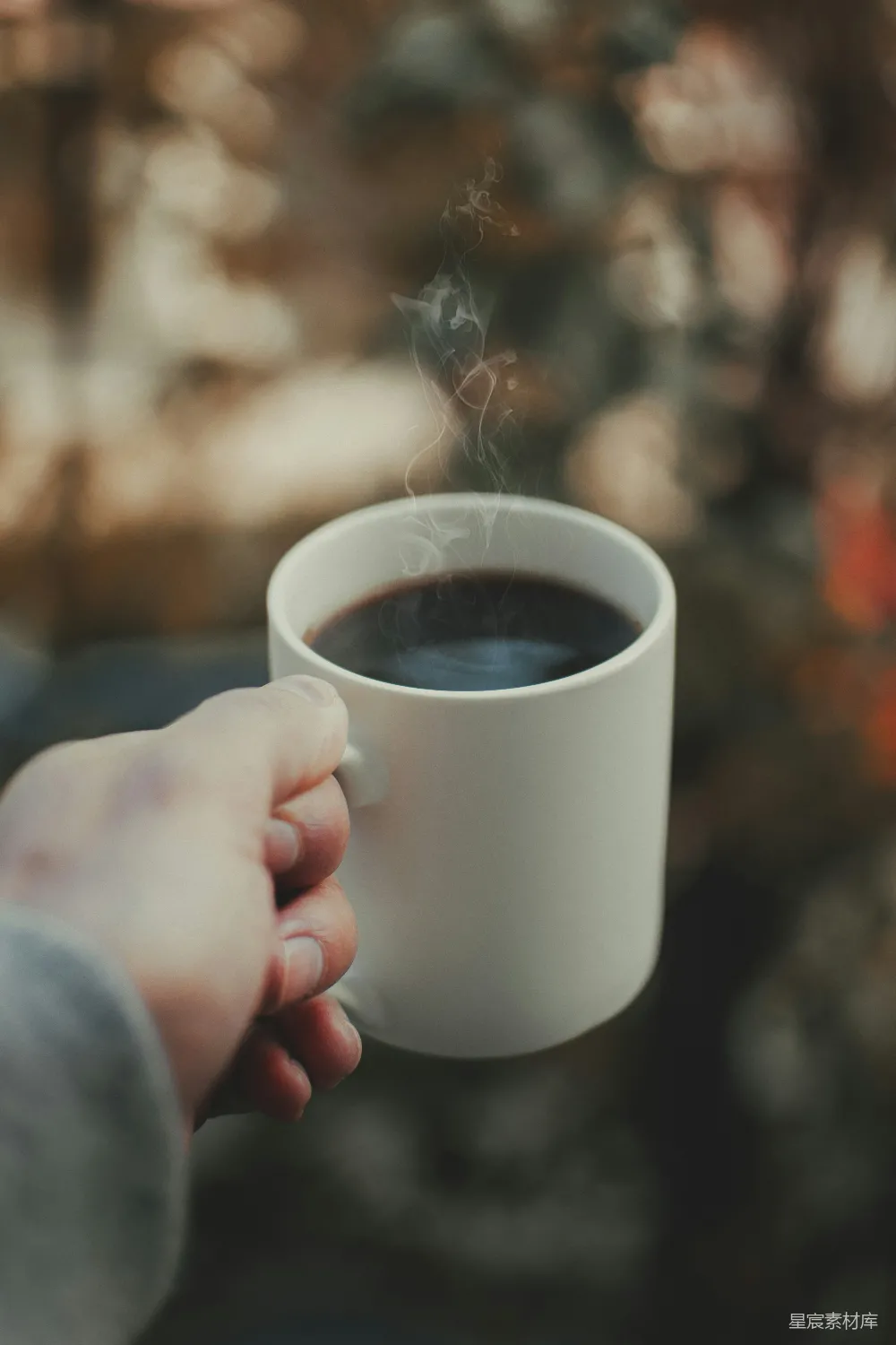 高清摄影  手持白色陶瓷 mug 的人手中拿着棕色液体