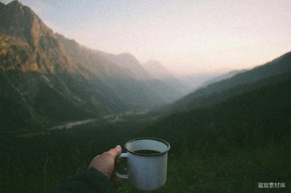 高清摄影  山间持杯的人手中握着一杯咖啡。