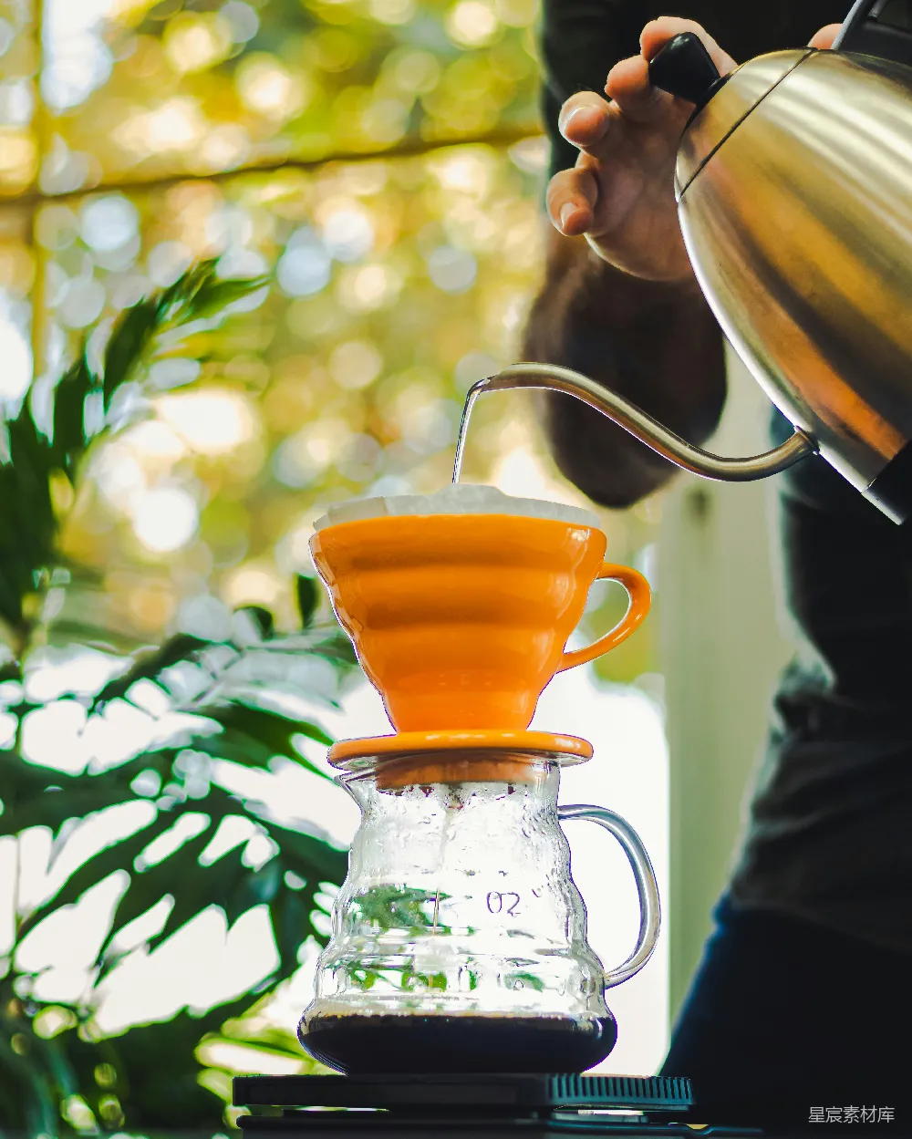 高清摄影  一个人往一个玻璃 pitcher 中倒橙汁。