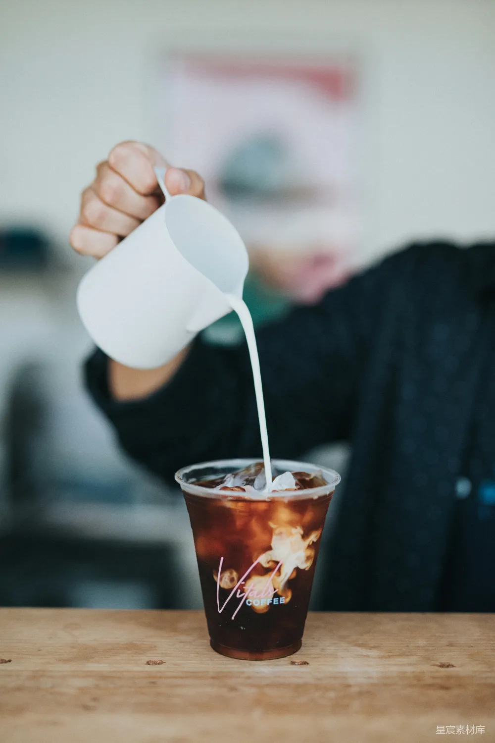 高清摄影  聚焦于手持杯并往塑料杯中加奶油的人的选拍摄法