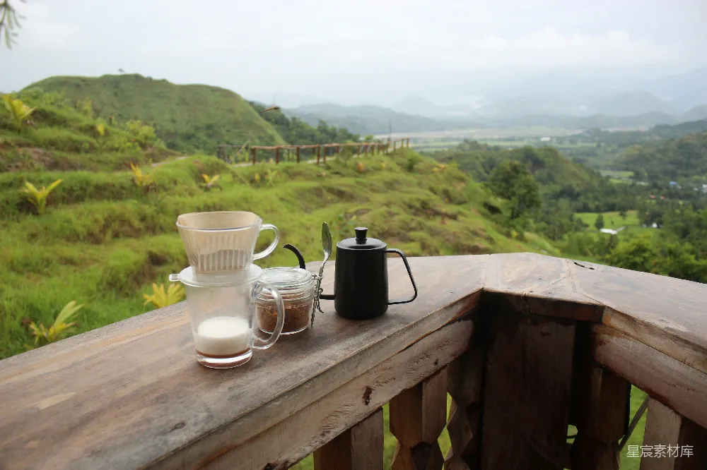 高清摄影  桌子上有杯子和茶杯，背景是草坡。