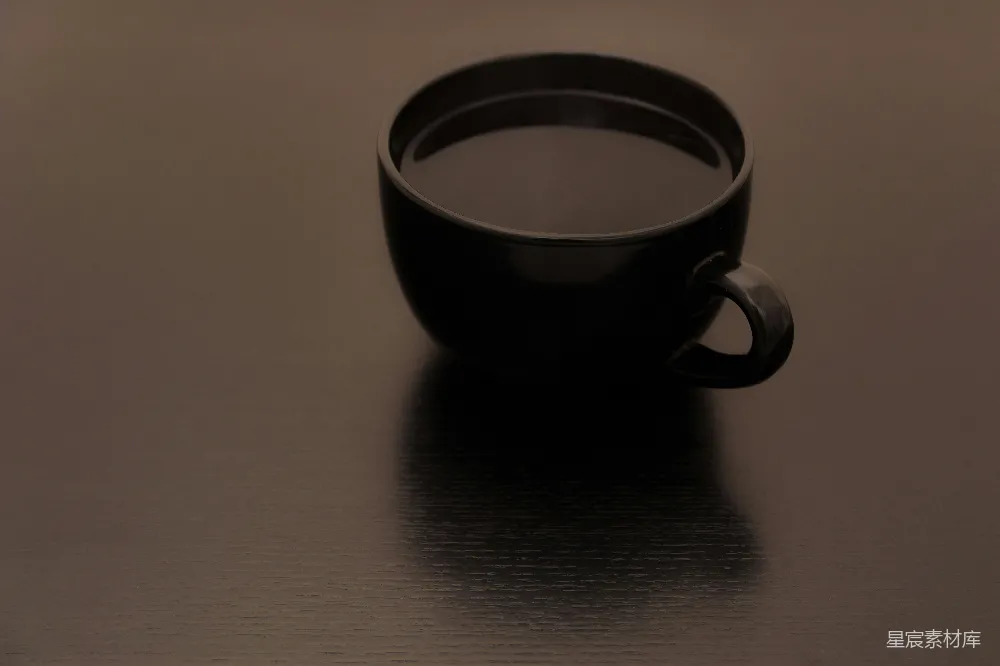 高清摄影 一个黑色的咖啡杯放在一个表面上。