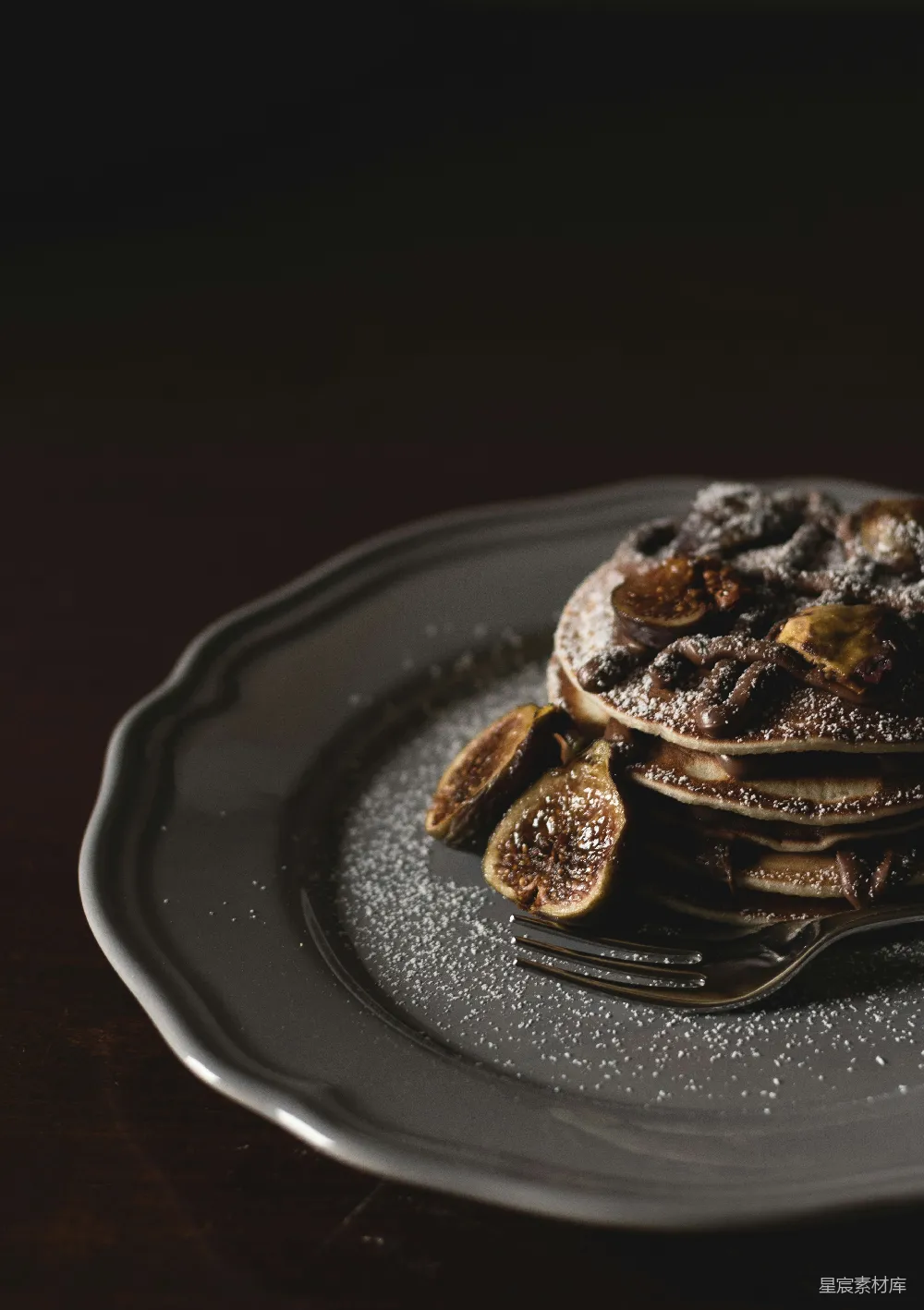 高清摄影  浅焦摄影：上面铺有香蕉片和 syrup 的 pancakes，放在灰色的盘子上。