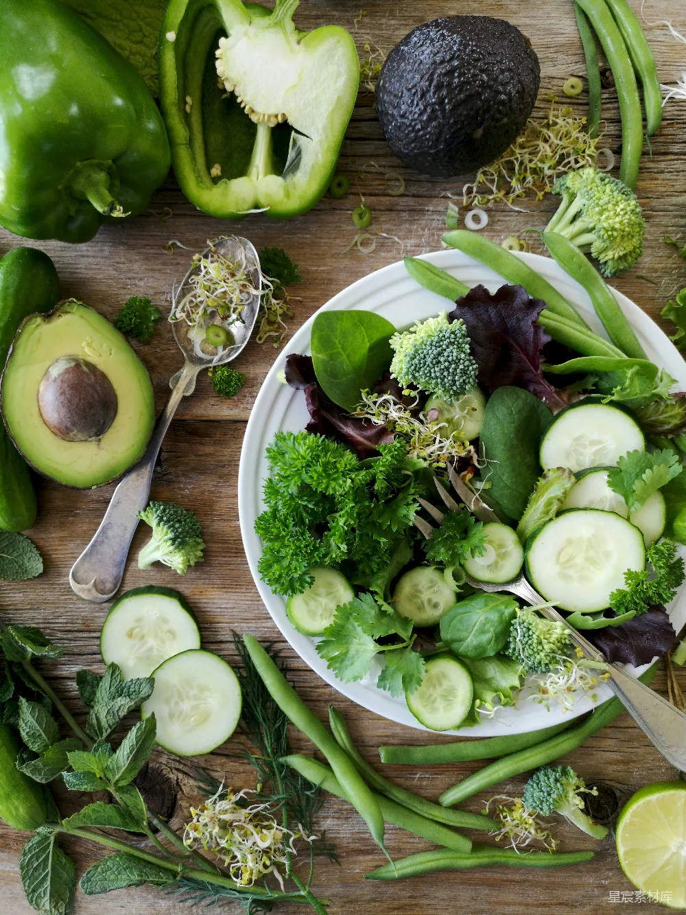 高清摄影 盘中切好的 broccoli 和 cucumber，旁边有一把灰色的不锈钢叉，靠近绿色的青椒、毛豆和牛油果果实。