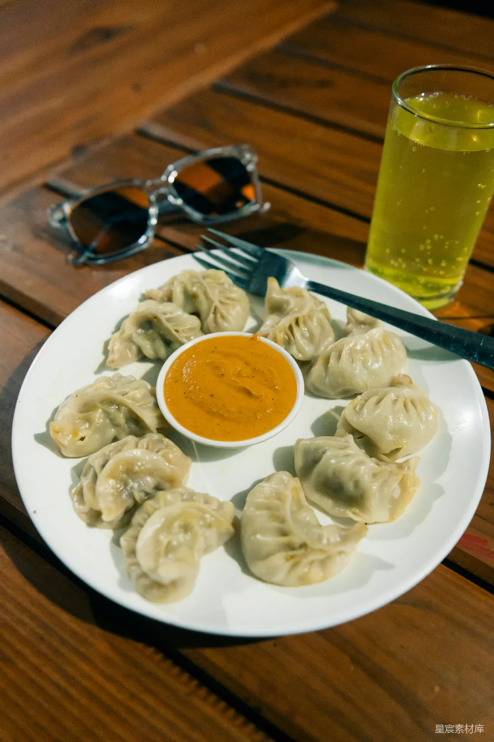 高清摄影 一个白色盘子上放着饺子，旁边是一杯酱料。
