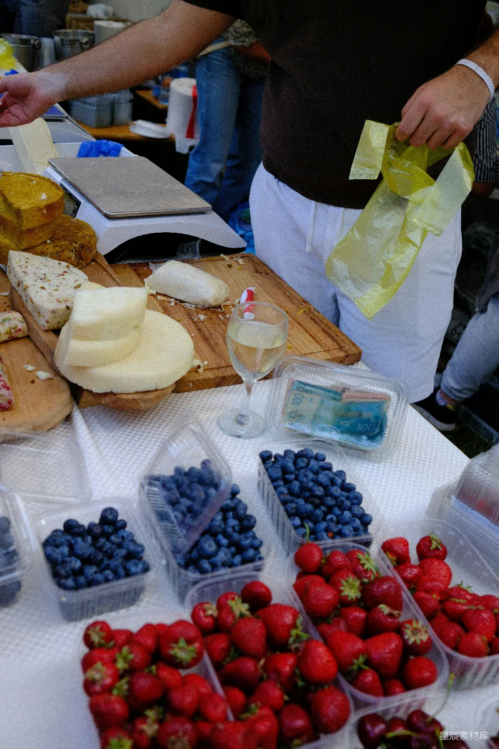 高清摄影 一个售卖奶酪、蓝莓、 strawberries 和白葡萄酒的市集小摊。