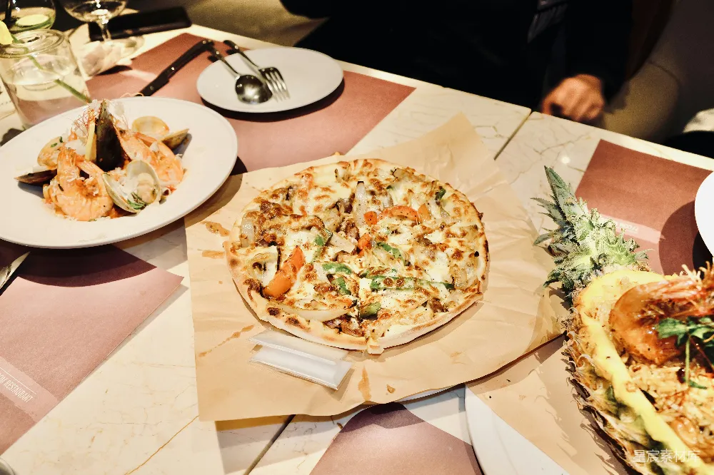 高清摄影 一张桌子上面摆放着装有食物的盘子和一个比萨饼