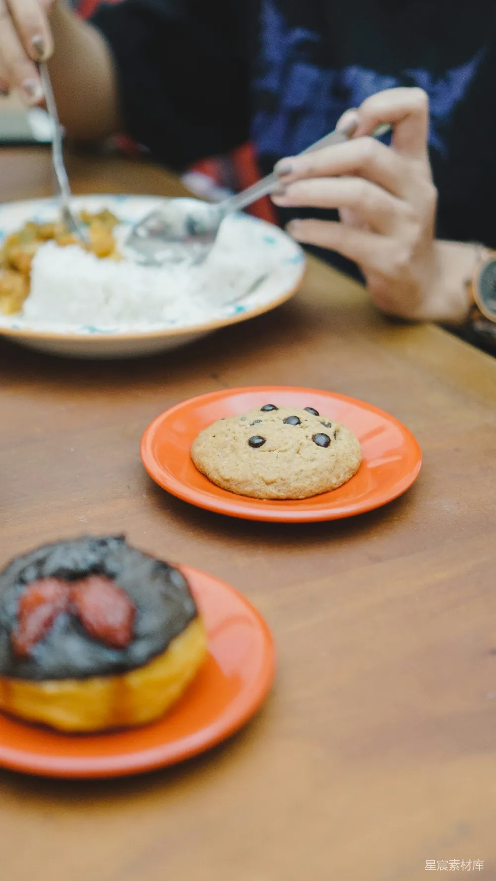 高清摄影 桌上摆放着装有甜甜圈的 plates，上面覆盖着奶油糖霜。