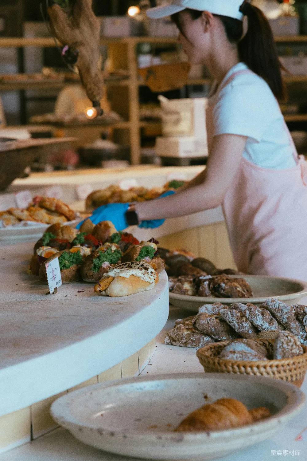 高清摄影 Baker正在面包店柜台处摆放点心。