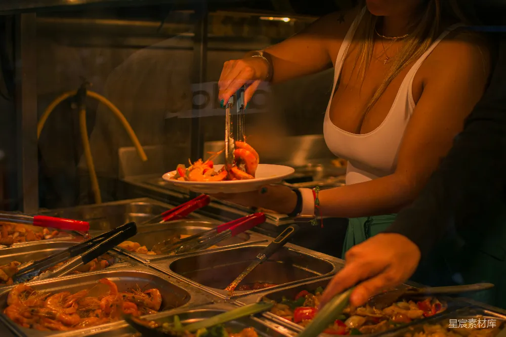 高清摄影 一个女人在自助餐台上切着一盘食物。