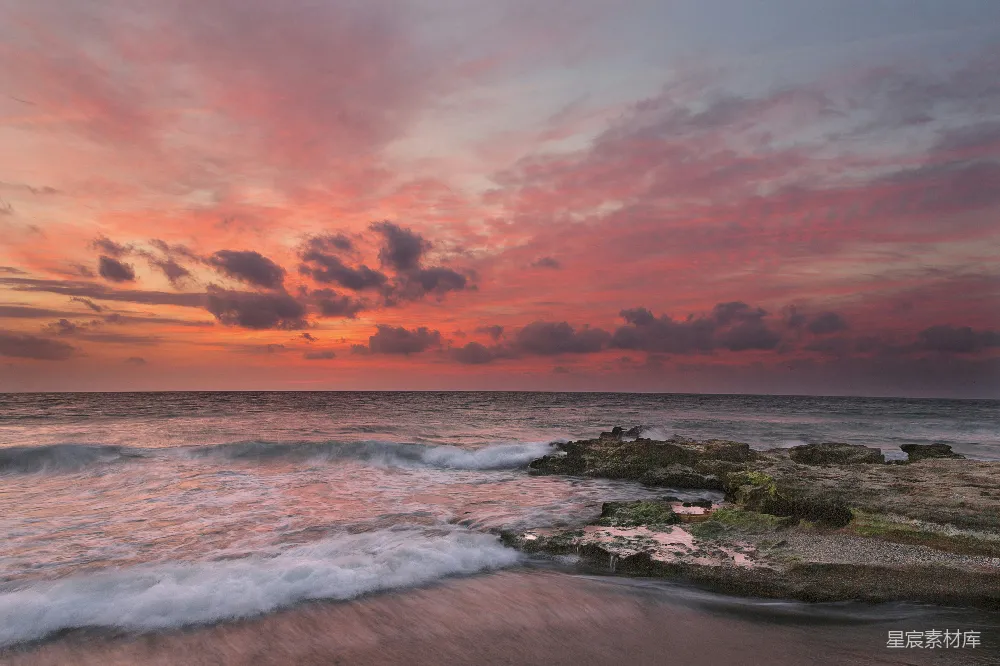 海边的日落时海水拍击着海岸浪花