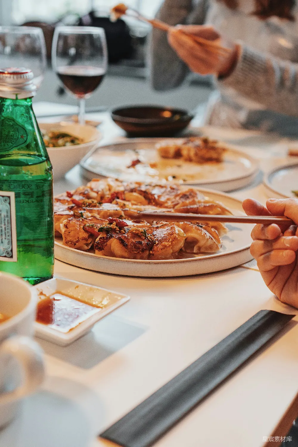 高清摄影 一群人在一张桌子上坐着，桌上放着盘子的食物。