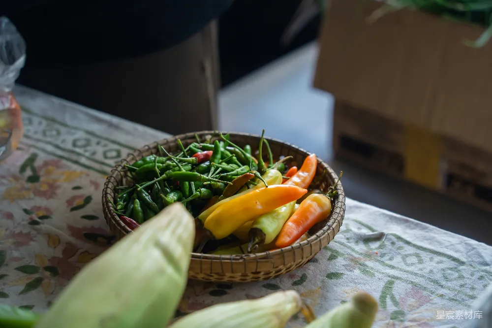 高清摄影 一个编织的篮子里面装满了绿色和橙色的辣椒。