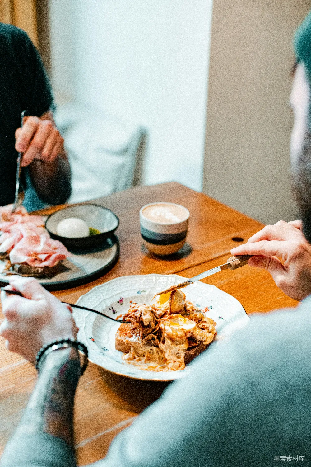 高清摄影  一个男人坐在桌子旁，桌子上有盘食物。