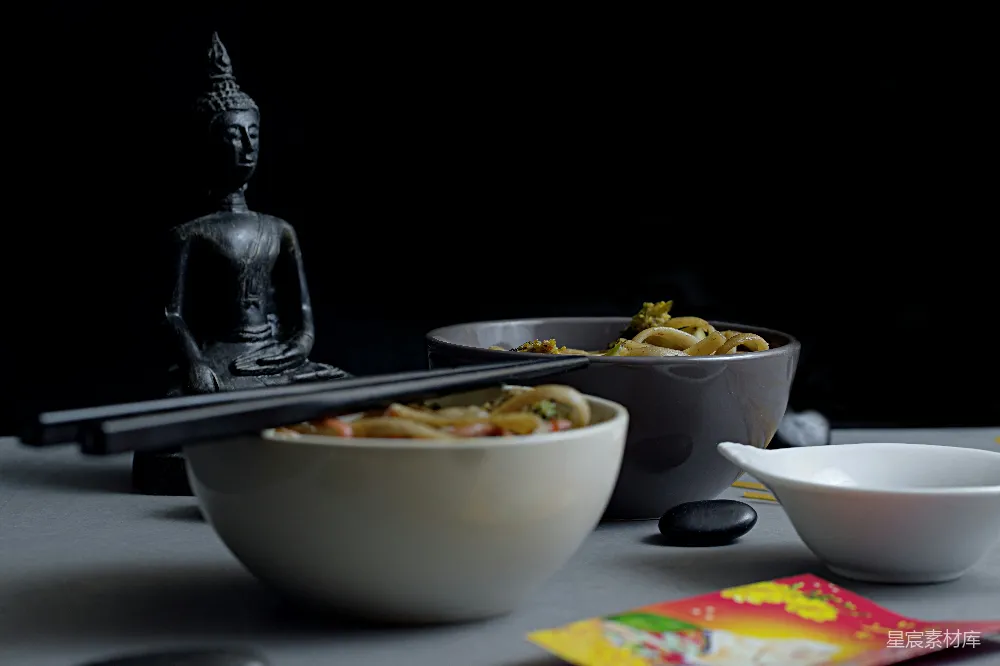 高清摄影  一张桌子上摆着装有食物的碗和一个雕像