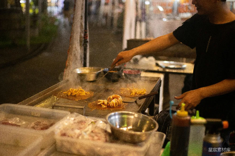 高清摄影  黑T恤的男人在平底锅里烹饪。