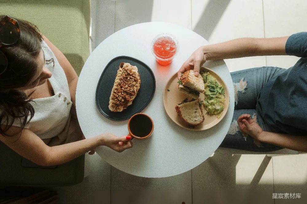 高清摄影  一位女性坐在桌子旁，桌上有一盘食物。