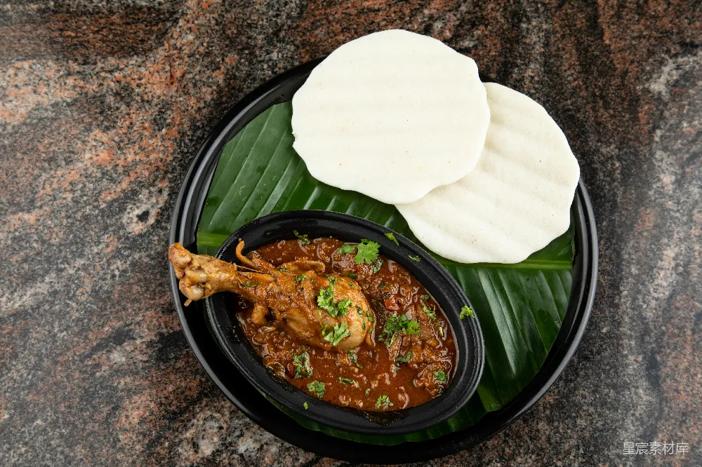 高清摄影  一块黑色的盘子上放着一道鸡肉 curry 和一些馕面包。
