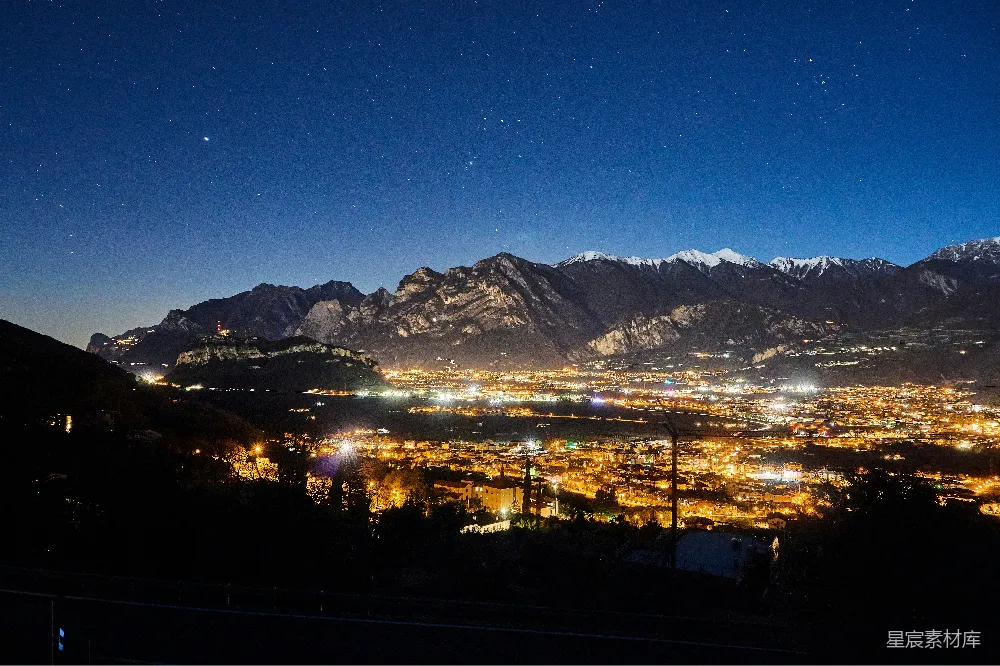 城市的夜晚景象，背景是山脉。