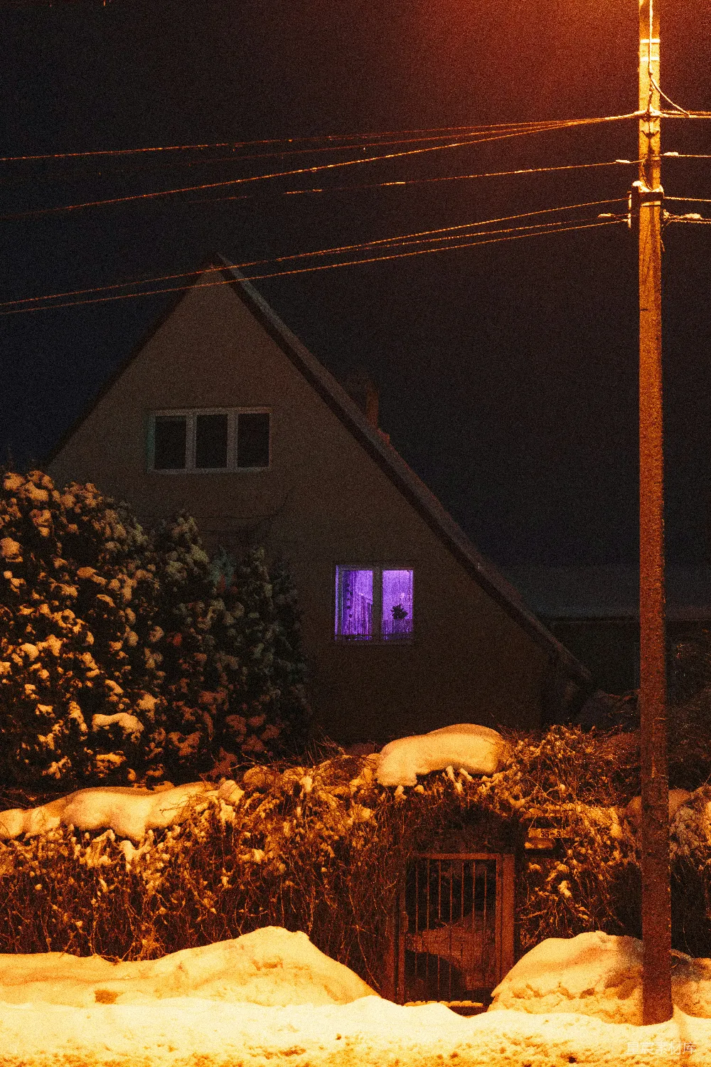 高清摄影  夜晚雪中房屋，窗户透出紫色光芒