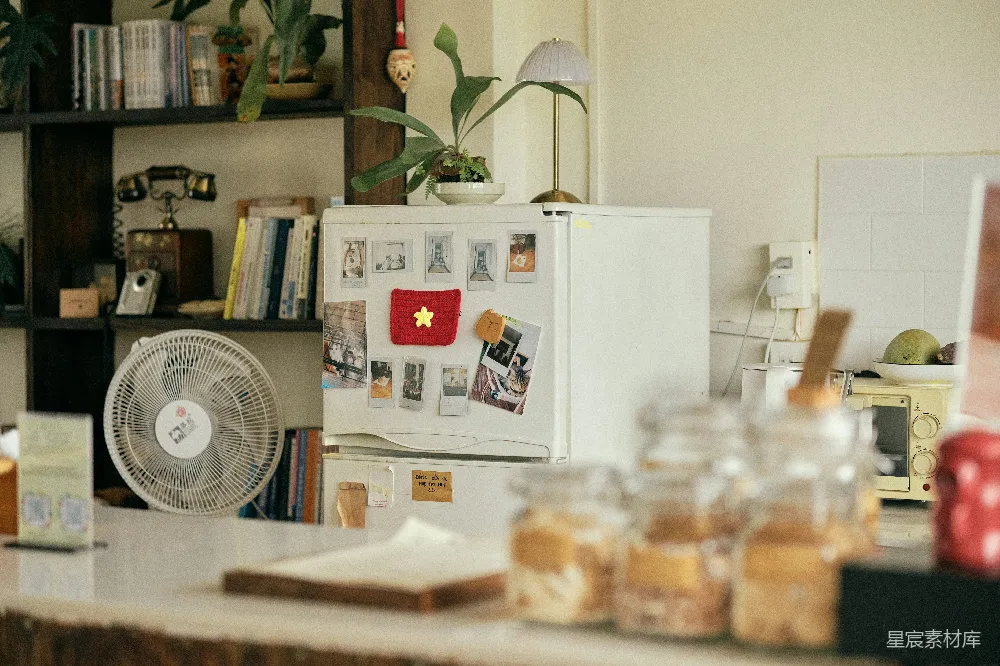 高清摄影  冰箱上有一个国旗磁铁、风扇和几个罐子放在柜台上。