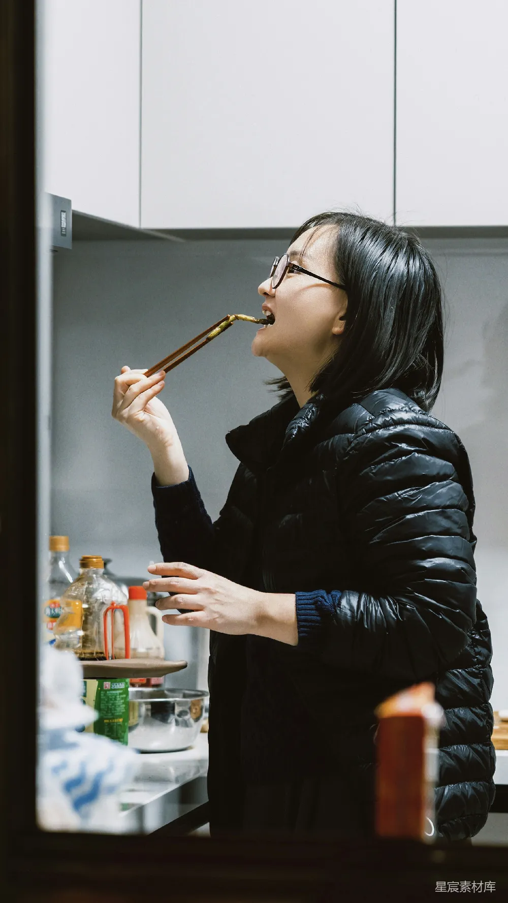 高清摄影  穿羽绒服的女人用筷子尝食物。