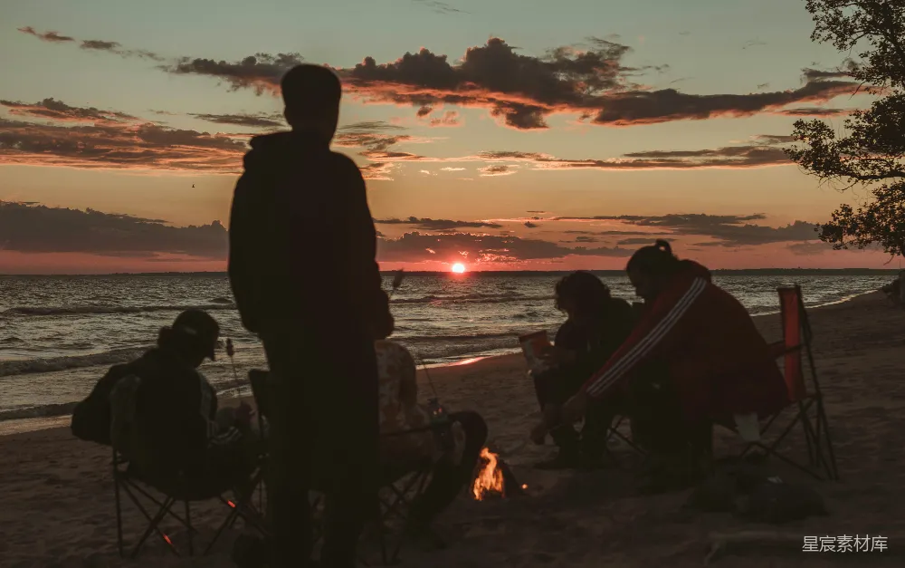 高清摄影 夕阳下，人们坐在水边的椅子上，剪影般地映衬在水面上。