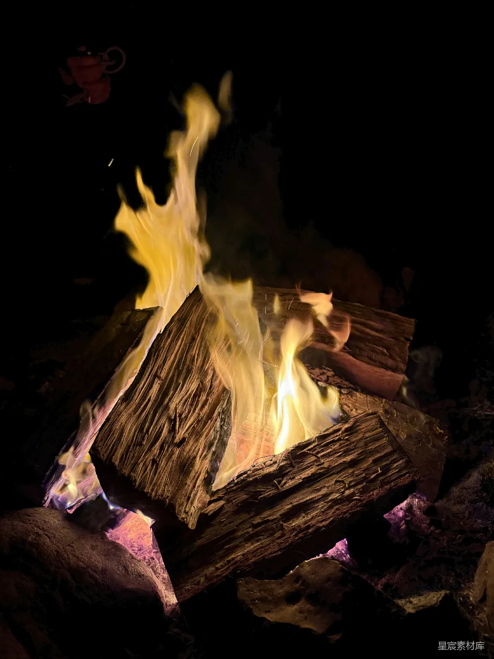 高清摄影  篝火在夜晚燃烧得明亮，周围有木头。