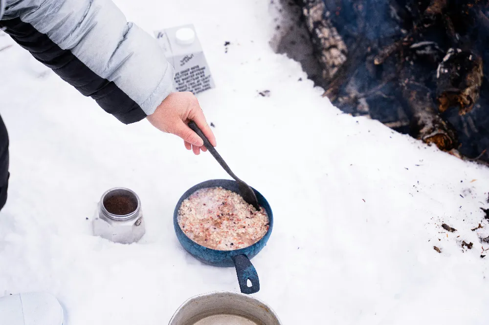 高清摄影  一个人在雪地上用平底锅做饭。