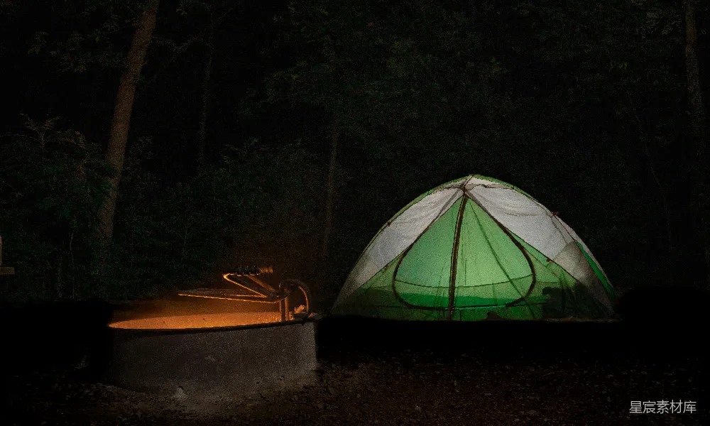 深夜的火势逐渐熄灭，只剩下烧成炭的灰烬和晚夏之夜中发光的绿色帐篷。