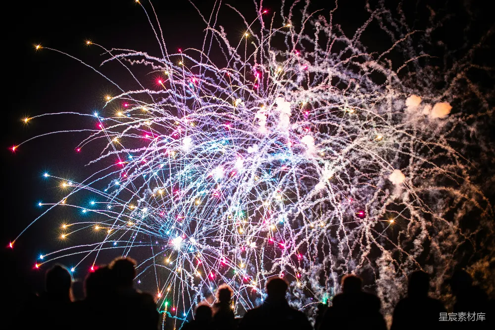 五彩缤纷的烟花表演。在英国哈斯廷斯的篝火夜庆祝活动中，绚丽多彩的烟花照亮了夜空。人们在蓝色、粉色和黄色的光芒中剪影。照片是用尼康D750相机和手动50mm镜头拍摄的。