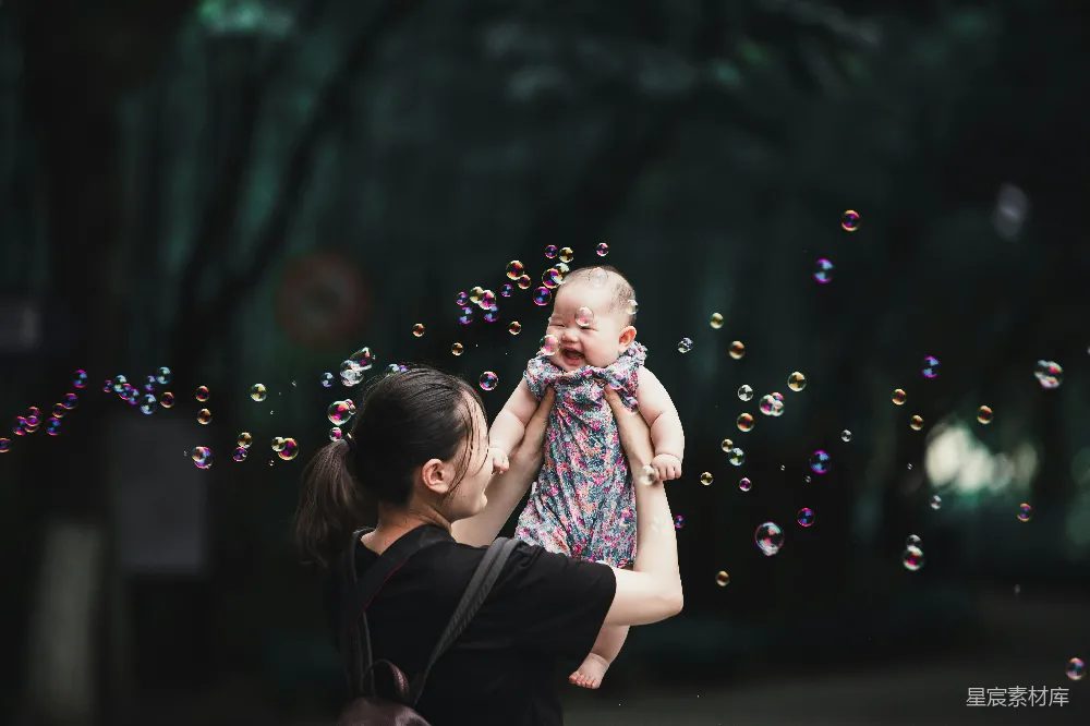 高清摄影  穿黑色和粉红色连衣裙的女孩在吹泡泡。