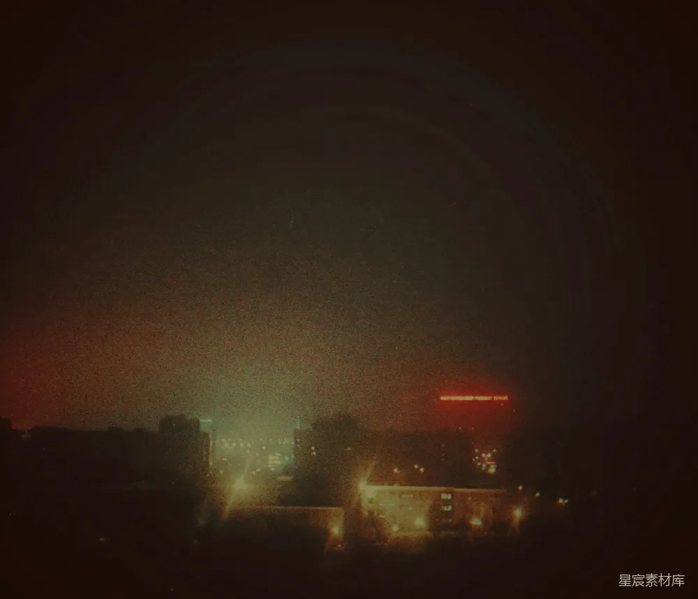 雾蒙蒙的城市夜景中闪烁着灯光和一个红色的招牌。