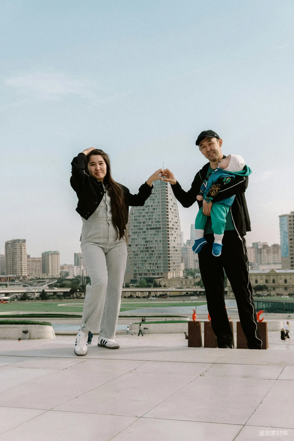 高清摄影  一对带着婴儿的夫妇站在屋顶上，俯瞰着城市建筑。