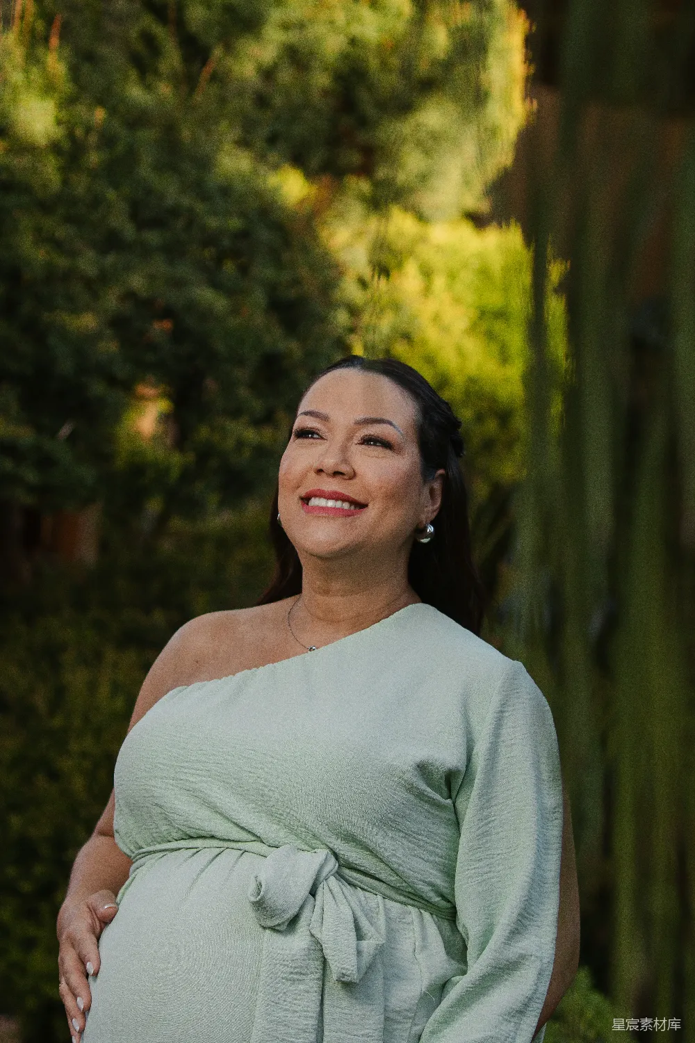 高清摄影  一位穿着浅绿色连衣裙的孕妇在户外微笑着。