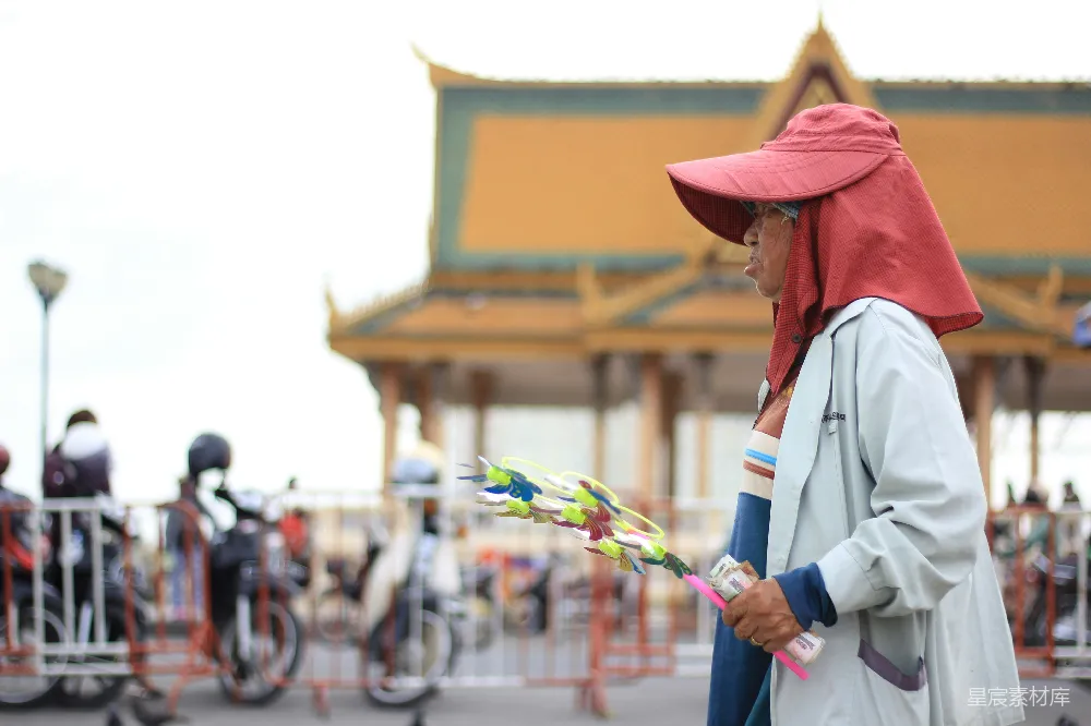 高清摄影  一个穿着白色长袖衬衫和棕色帽子的人，手里拿着一把白色和绿色的塑料伞。