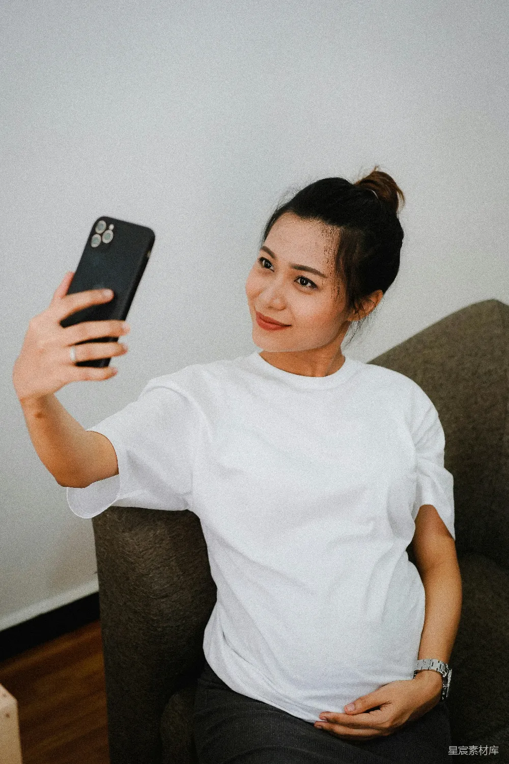 高清摄影  穿白色圆领T恤的女人手里拿着黑色的iPhone 7 plus。