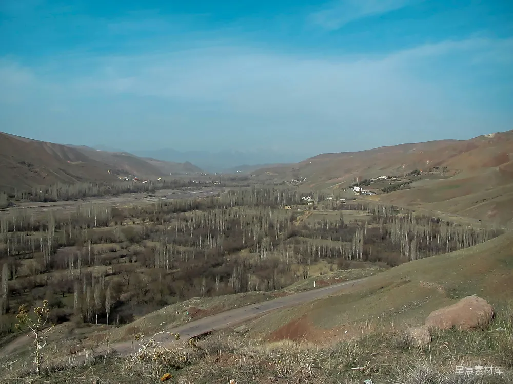 高清摄影  一幅山间谷地的美景，背景中有树木和山脉。
