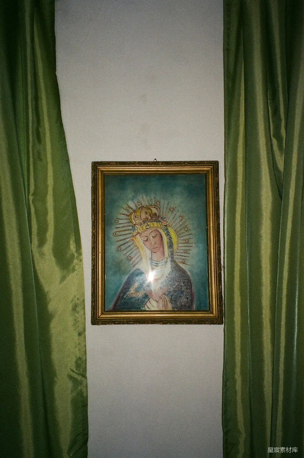 高清摄影  一幅挂在绿色窗帘前的圣母玛丽亚的画。