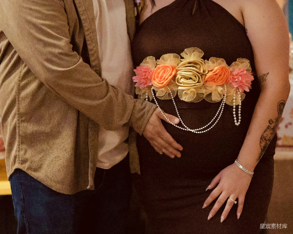 高清摄影  孕妇腰间系着花边肚带，伴侣的手放在她的手上。
