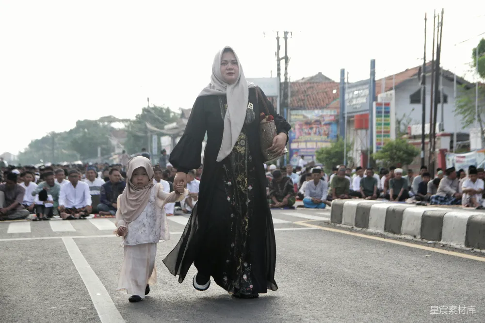 高清摄影  一对妇女和孩子在街上行走，旁边有人在祈祷。