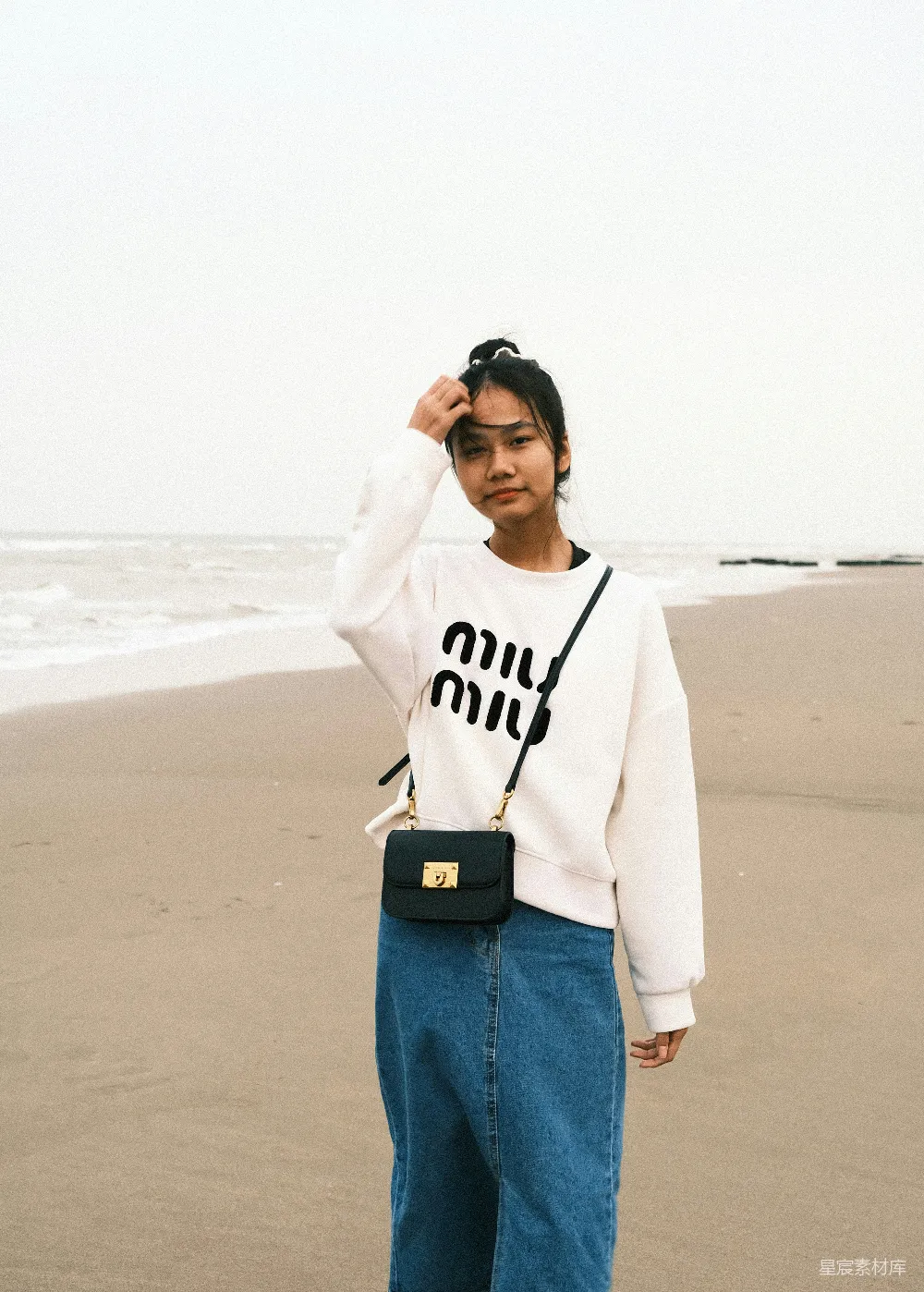 一个女人站在海滩上，旁边是海洋。