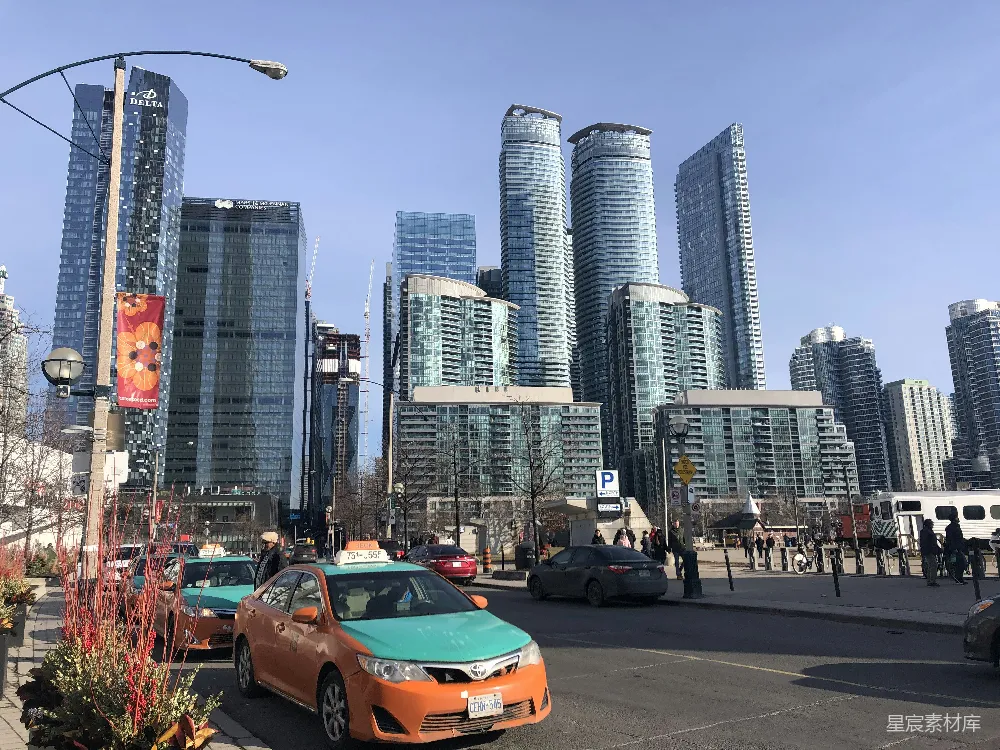 高清摄影  白天，城市建筑附近路上的一辆橙色汽车。