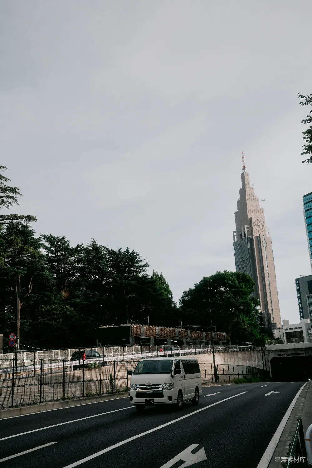 高清摄影  一辆面包车在摩天大楼旁的道路上行驶。