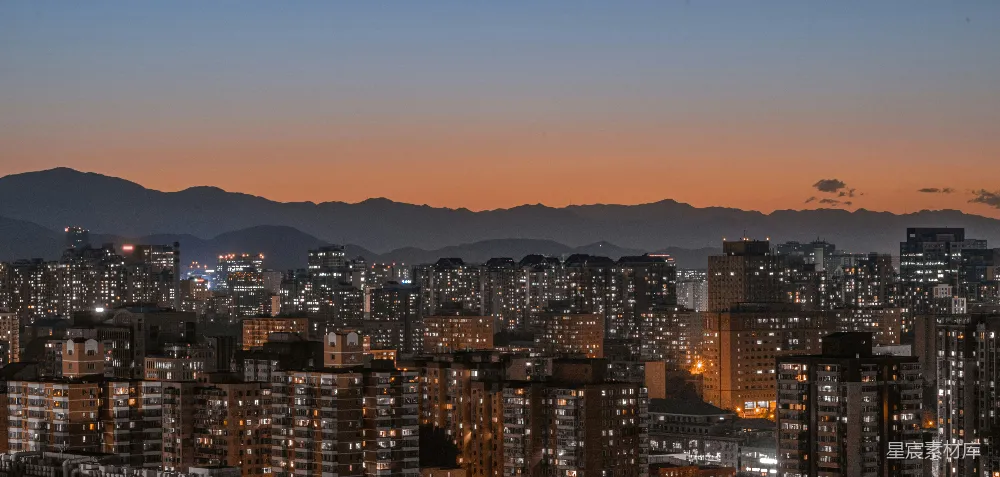 高清摄影  夜晚的城市景色，背景是山脉。