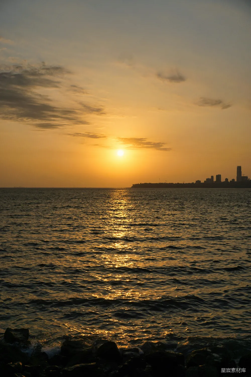 高清摄影 夕阳落下海面上，远处有一座城市。