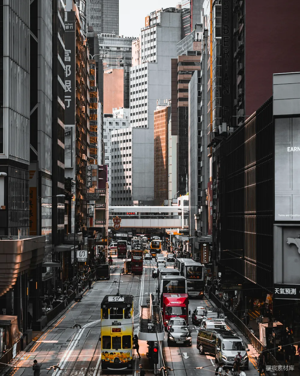 高清摄影  在白天，红白相间的公交车行驶在高楼大厦之间的道路上。