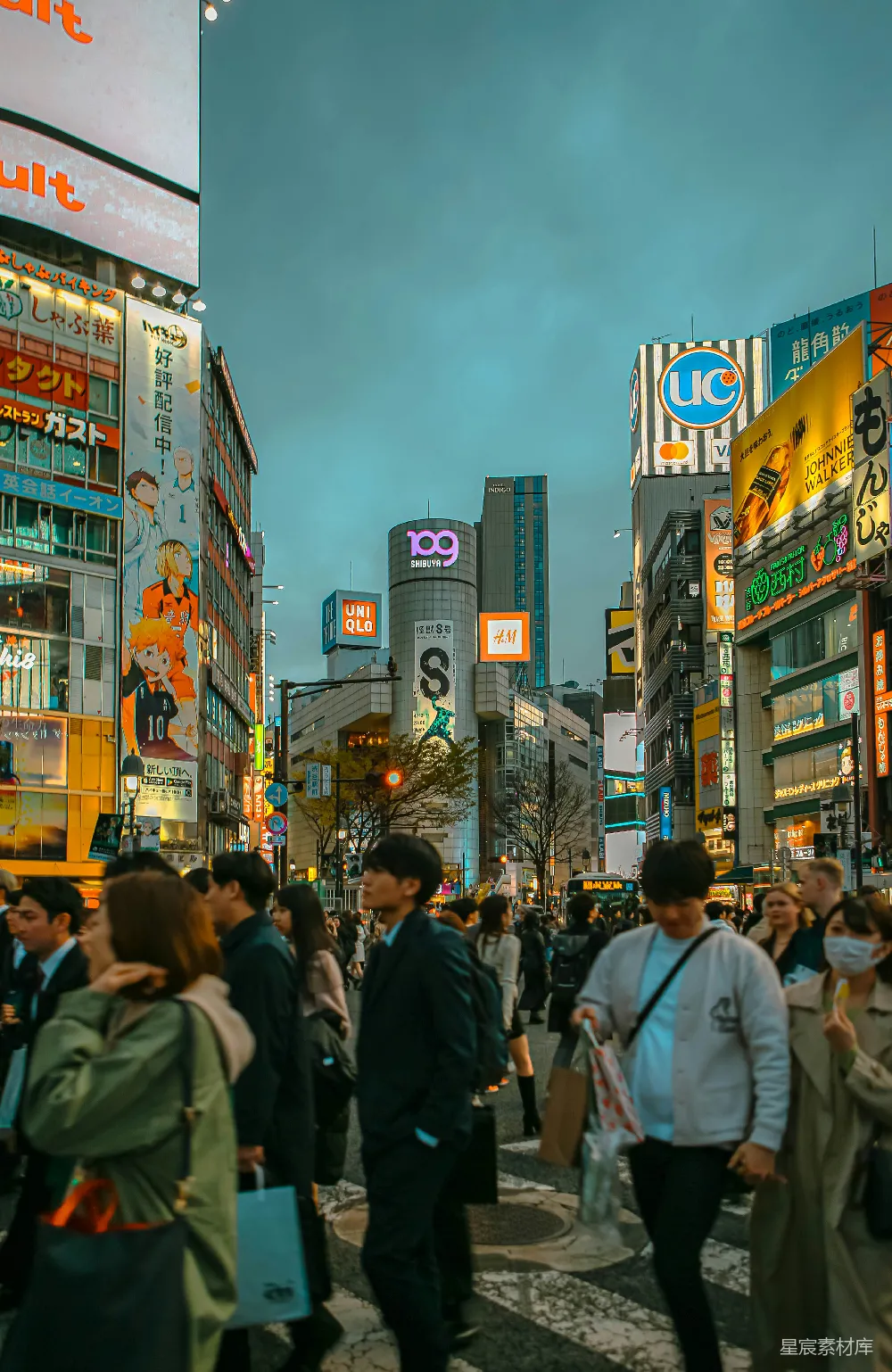 高清摄影 旅行 一群人走在高楼旁边的一条街上。