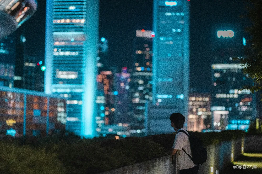 高清摄影  一个人站在夜晚城市前的墙上。